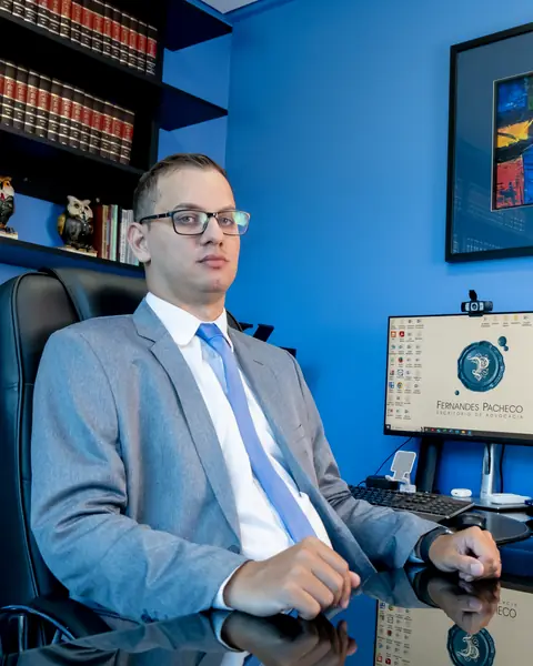 Dr. Guilherme Sartori Pacheco, sentado à mesa no escritório